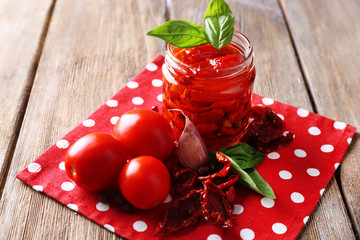 Sun dried tomatoes in glass jar, basil leaves