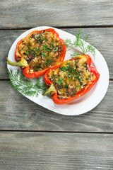 Stuffed red peppers with greens on plate on wooden table