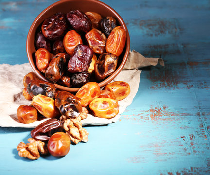Tasty dates fruits in bowl, on blue wooden background