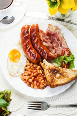 Full English breakfast with bacon, sausage, fried egg and baked