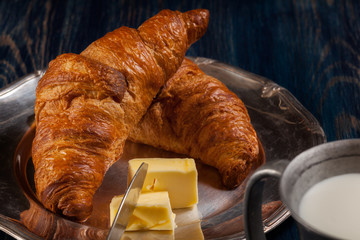 Croissants with butter and a glass of milk