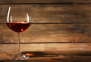 Goblet of red wine on wooden table on wooden wall background