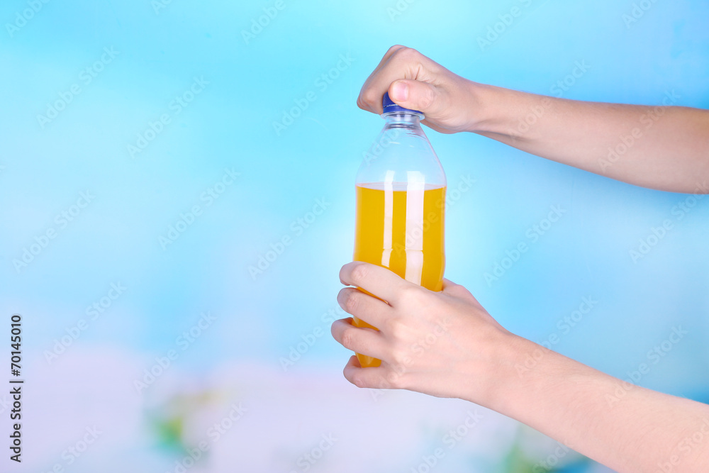 Wall mural hand opening bottle with sweet water on sky background