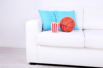 Popcorn and basketball on sofa in room