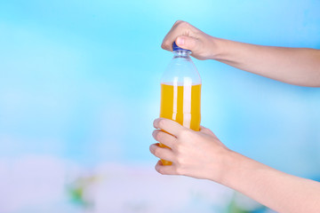 Hand opening bottle with sweet water on sky background