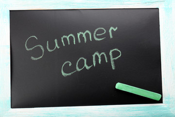 Text Summer camp written with chalk on chalkboard, close-up