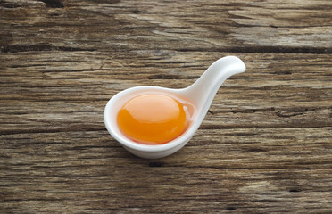 Egg yolk in the modern spoon on table wooden
