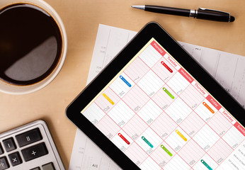 Tablet pc showing calendar on screen with a cup of coffee on a d - obrazy, fototapety, plakaty