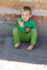 cheerful little boy near a brick wall