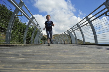 Fototapeta na wymiar Boy running on the mountain bridge