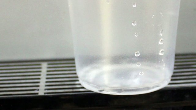 Male hand serving water of a water cooler in plastic cup
