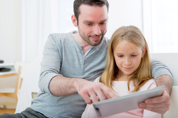 Father and his blond daughter using tablet