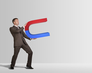 Businessman in suit holding big magnet