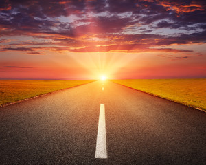 Obraz premium Jazda po pustej drodze asfaltowej o zachodzie słońca