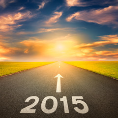 Driving on an empty road towards the sun to 2015