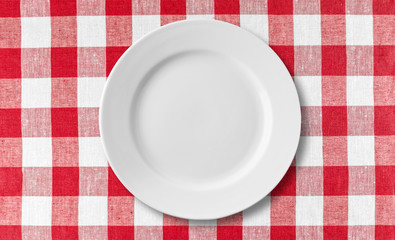 Empty white plate on checkered red tablecloth
