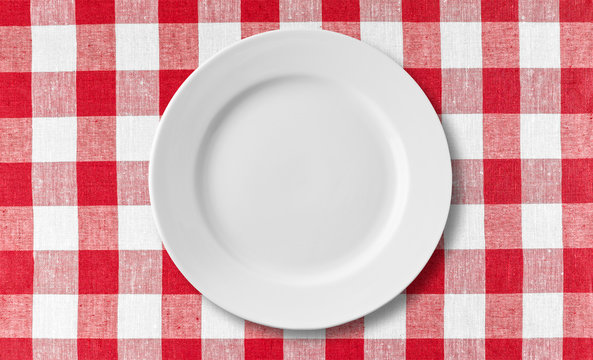 Empty white plate on checkered red tablecloth
