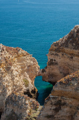 Algarve coast, Portugal. Rocks in the shoreline and blue water