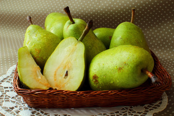 Green pears in a basket and one of them cut into the share.