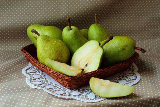 Green pears in a basket and one of them cut into the share.