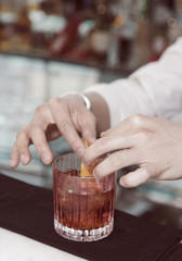 Barman is decorating drink with lemon zest