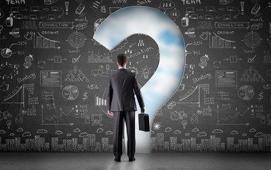 Businessman looks through a hole in wall
