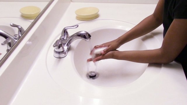 Young girl washing her hands in bathroom sink.