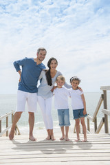 happy family  standing on a wood pontoon in front of the sea in