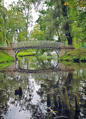 Fototapeta na wymiar Picturesque landscape with old bridge over flow in the park
