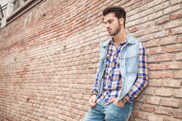 man leaning on a wall with his hand in pocket