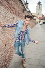 handsome man leaning on a brick wall, in the city