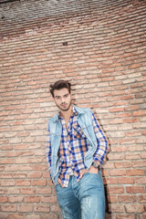 cool young man leaning on a brick wall