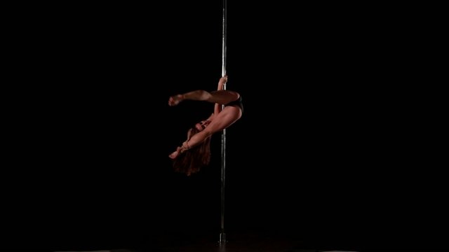 Sexy female pole dancing on black background