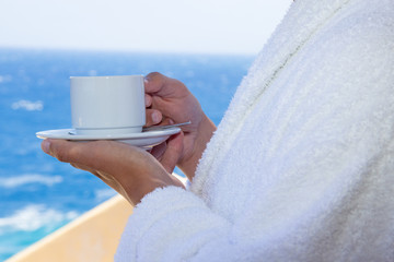 cup of coffee in male hands over sea view