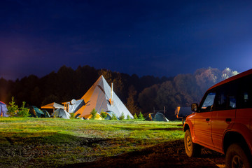 Tents in the tourist camp in a forest glade. Night.