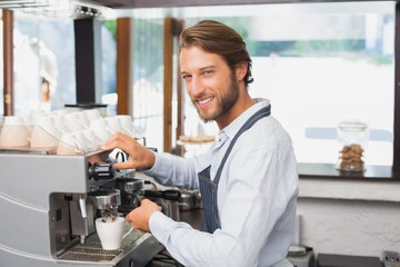 Naklejka na ściany i meble Handsome barista making a cup of coffee