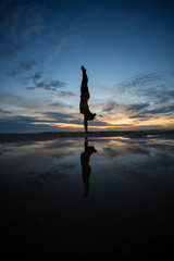 girl doing handstand on beach in sunset