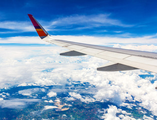 Fototapeta na wymiar Wing of the plane on sky background - plane wing with cloud patt