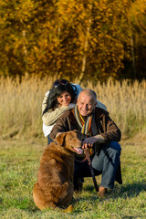 Fototapeta premium Cheerful couple with dog in autumn countryside