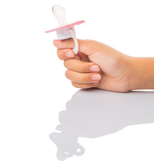 Female hand holding pink pacifier over white background
