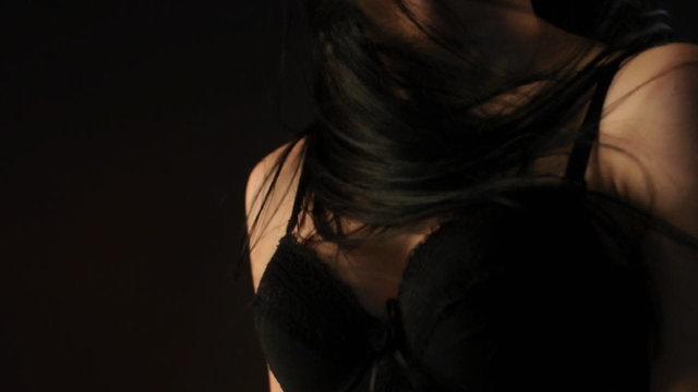 Sexy brunette woman in black lingerie dancing in the dark