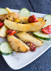 baked potato and raw vegetables on a white plate, closeup