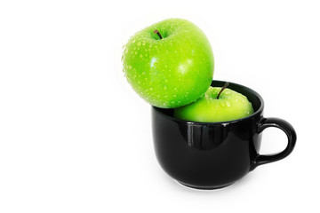 fresh green apple in black ceramic cup on white background