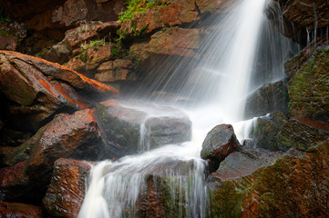 Wet rocks and splashes of water on mountain river waterfall