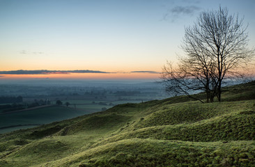 Stunning sunrise over fog layers in countryside landscape