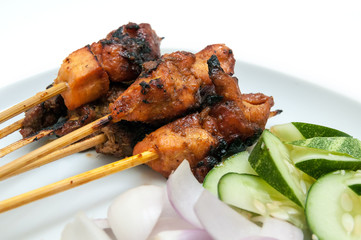 Delicious satay with cucumbers and onions served on white plate