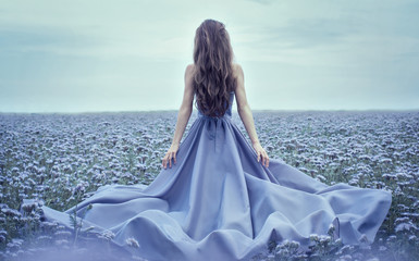 Back view of standing young woman in blue dress - Powered by Adobe