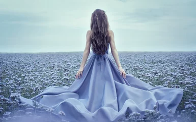 Rückansicht der stehenden jungen Frau im blauen Kleid © kiuikson