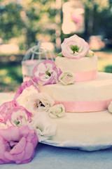 Beautiful wedding cake with flowers on table, outdoors