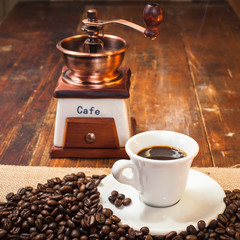 Cup of black coffee in the background grinder on a wooden rustic